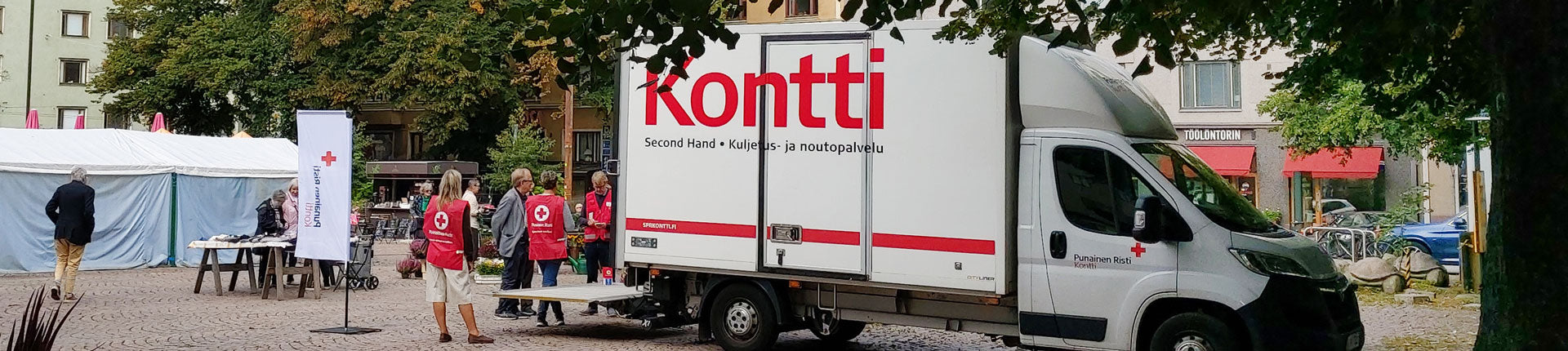 Torilla iso valkoinen pakettiauto, jonka kyljessä Kontti-logo. Auton luona punaliivisiä ihmisiä.