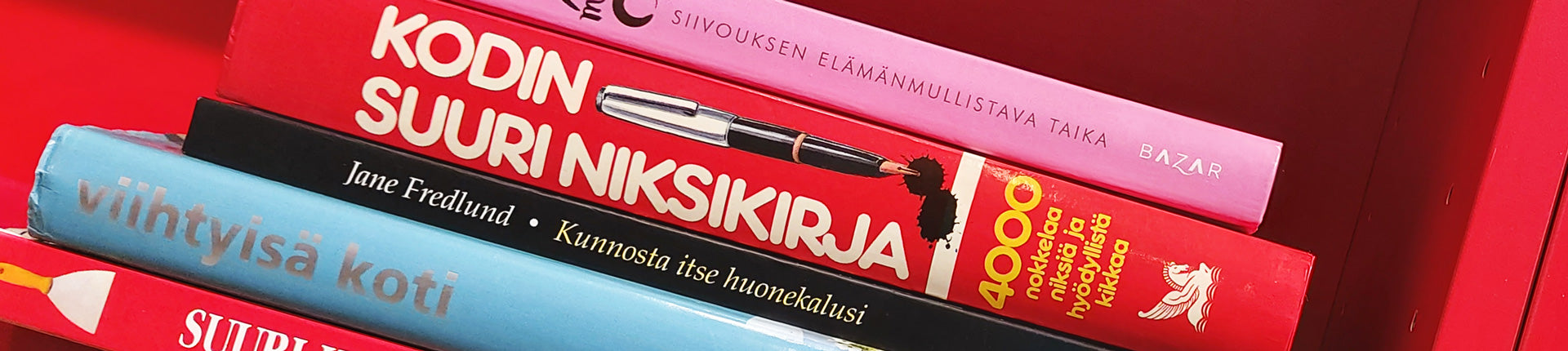 Punaisessa kirjahyllyssä kodin ja huonekalujen kunnostamiseen ja järjestämiseen liittyviä opaskirjoja.