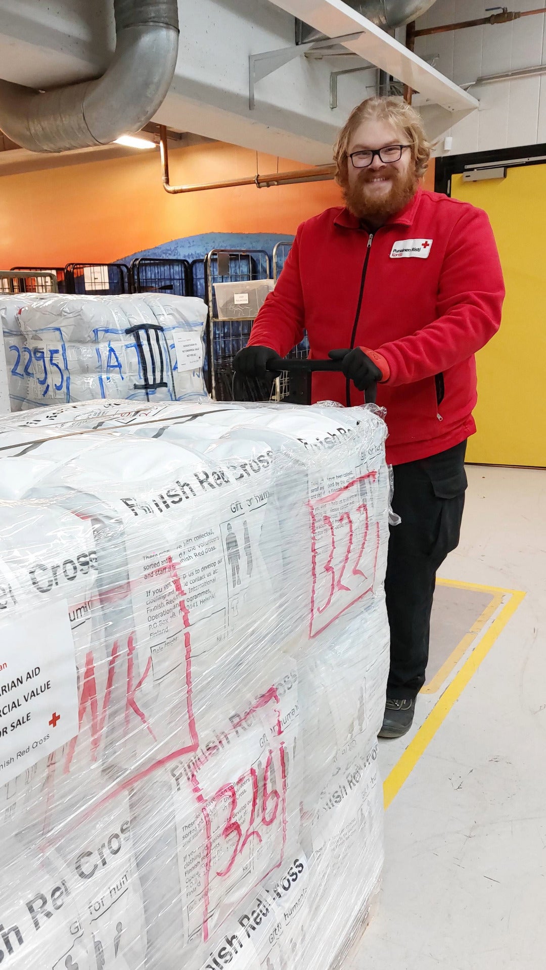 Kontin työntekijä lastaa vaateapupaaleja Kontin logistiikkakeskuksessa.