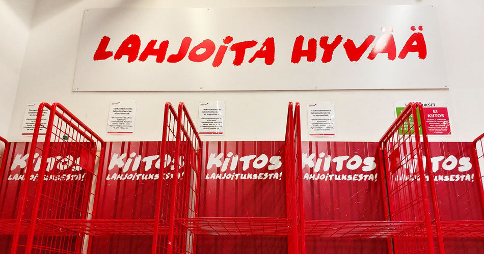 Viisi punaista lahjoitusrullakkoa rivissä ja kyltti Lahjoita hyvää.