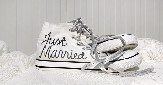 Hyllyn päällä valkoiset tennarit, joihin on tussilla kirjoitettu Just Married