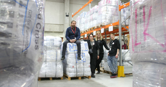 Henkilöitä logistiikkakeskuksen varastohyllyjen keskellä