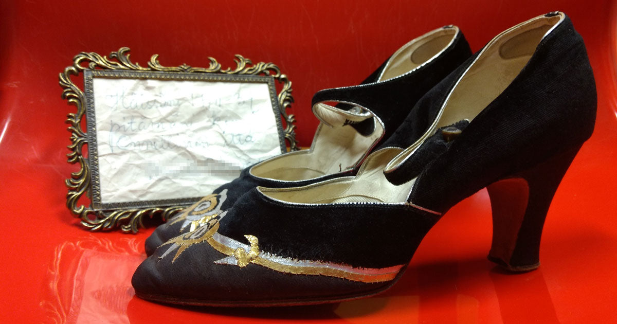 Mustat, kulta-hopea-kirjaillut vanhat remmikengät punaista taustaa vasten.