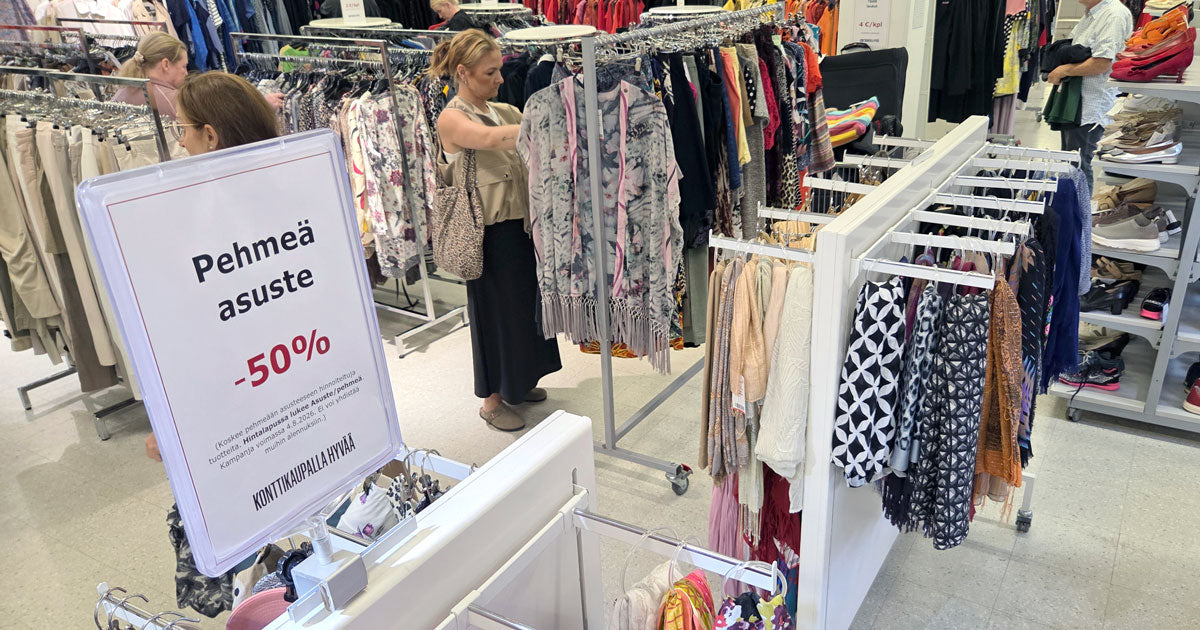 Myymälän vaateosastoa, asiakkaita ja etualalla etuhinnoista kertova kyltti. 