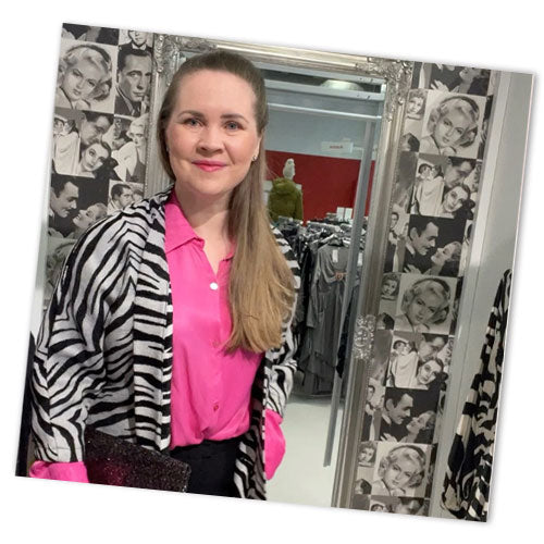 Hymyilevä henkilö seisoo sovituskopissa myymälässä