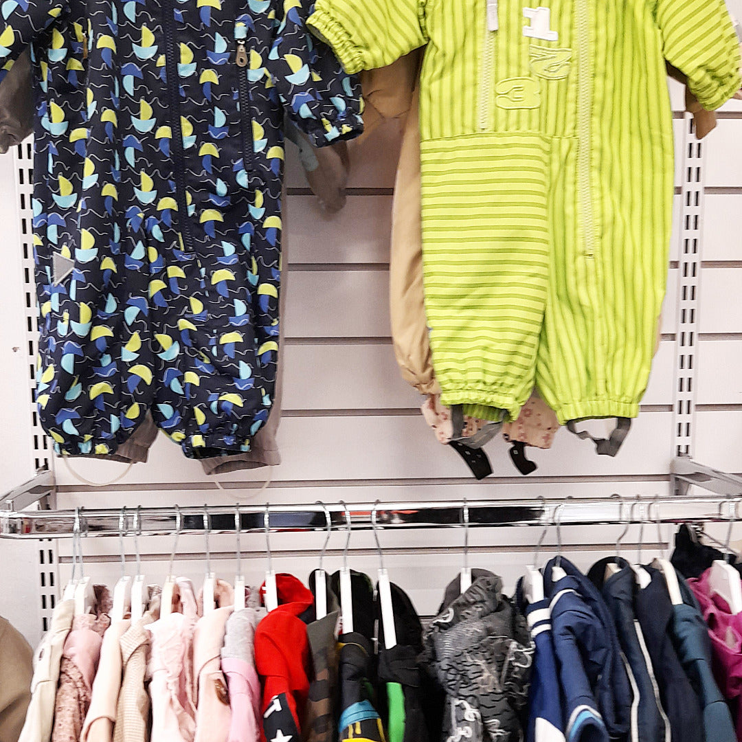 Lasten ulkovaatteita rekissä ja seinällä.