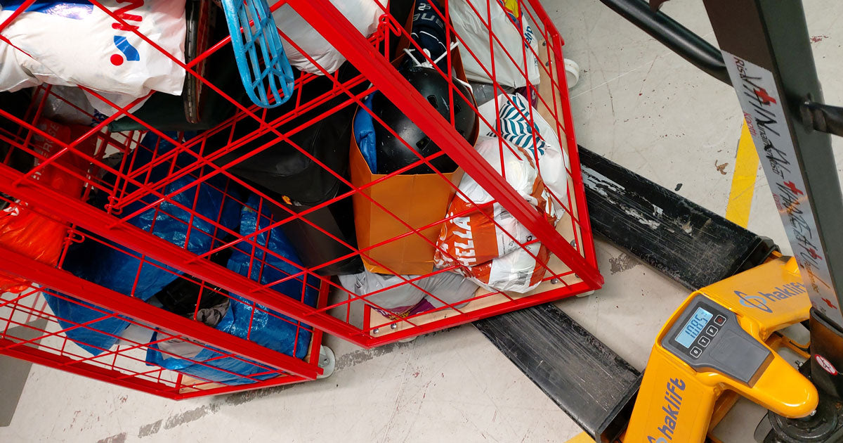 Punaiset rullakot täynnä lahjoituskasseja. Toista punnitaan pumppukärryvaa'alla, ja paino on 108,5 kiloa.