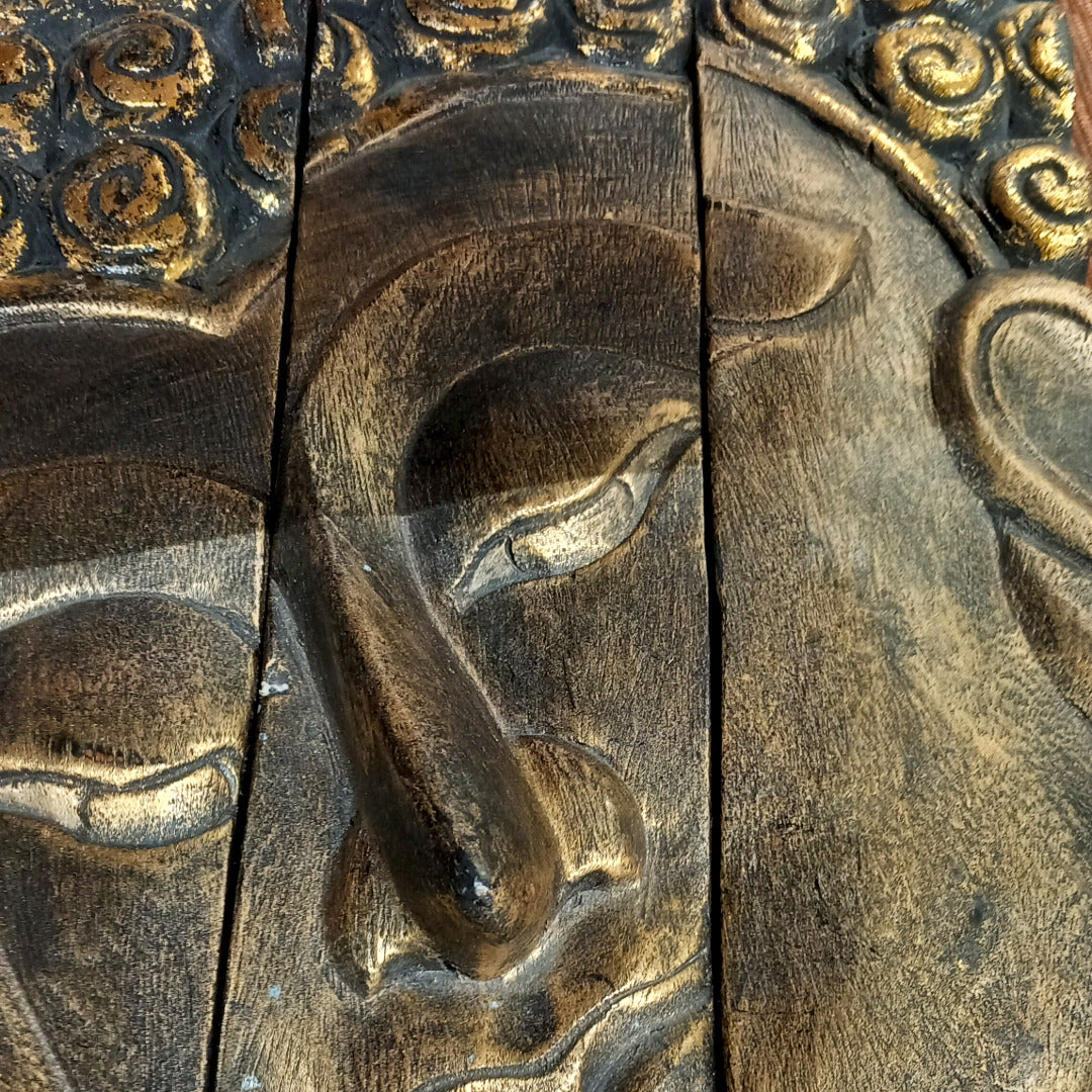 Pronssinvärinen buddhaa esittävä laatta.