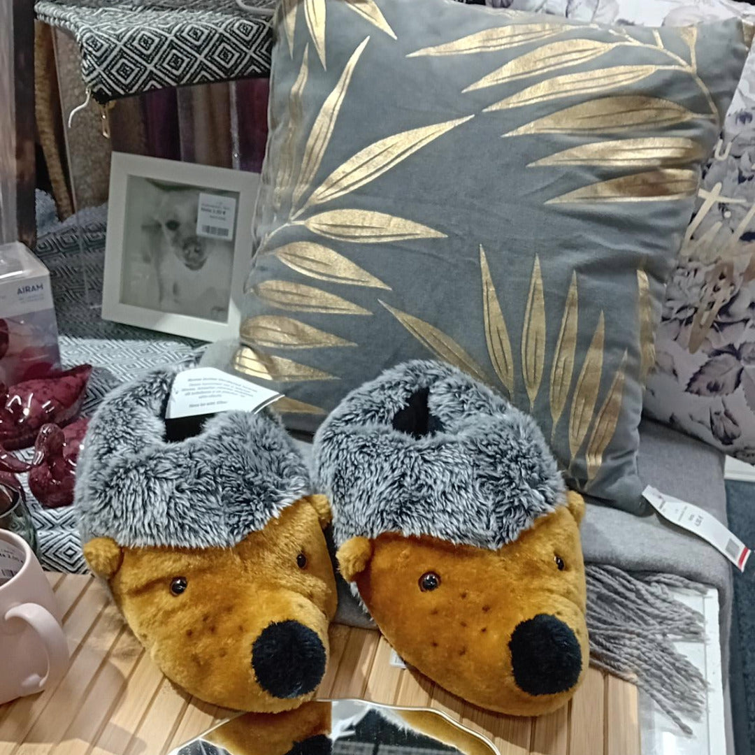 Siilitohvelit, harmaa/kulta-sisustustyyny ja harmaita torkkupeittoja.
