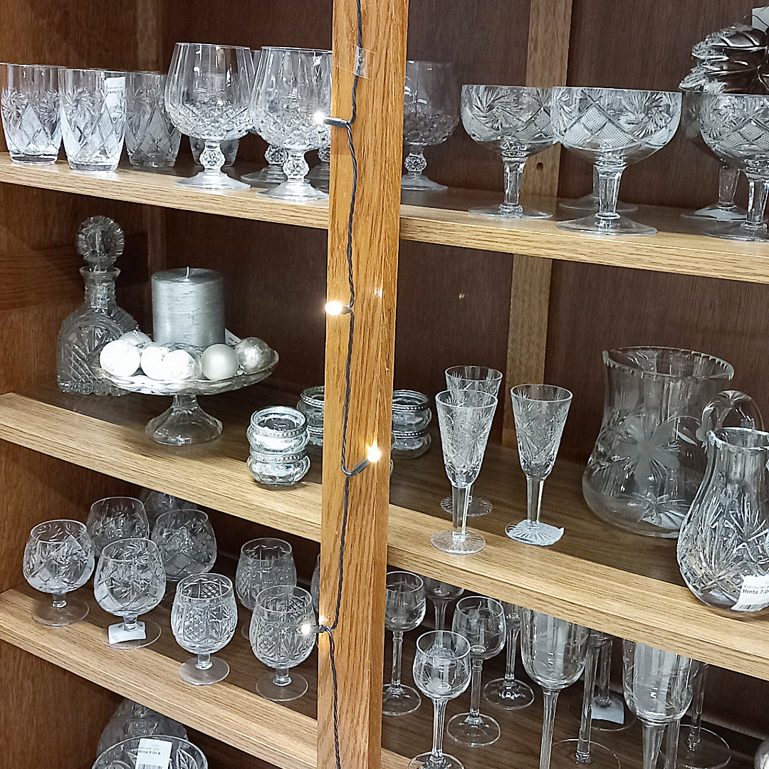 Erilaisia kristallilaseja puuhyllyssä.