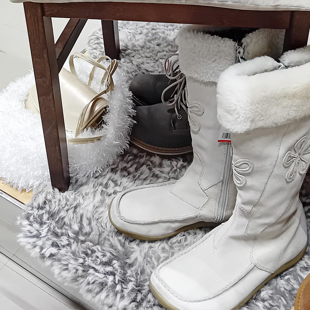 Valkoiset talvisaappaat ja vaalea käsilaukku.