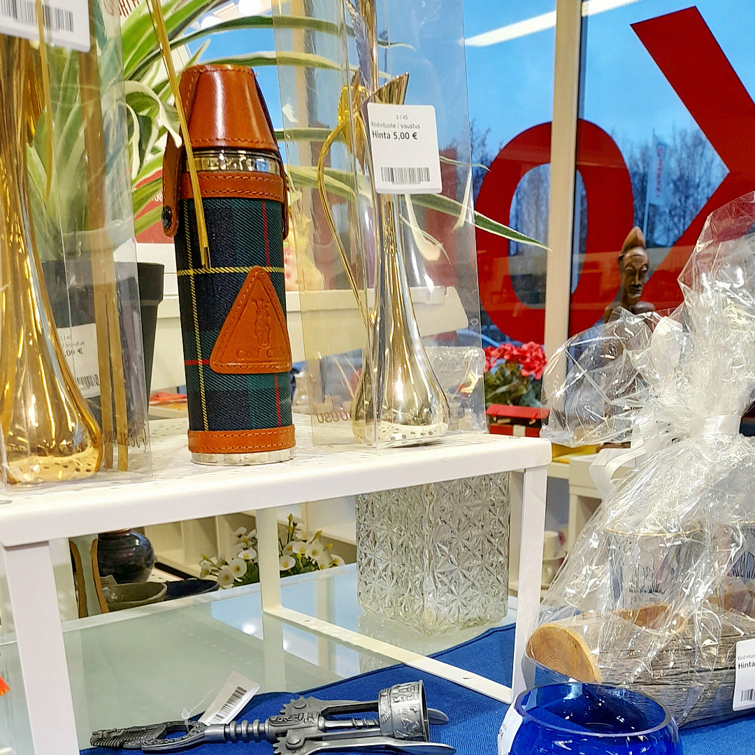 Pöydällä ja pikkuhyllyllä maljakoita, termospullo, viinipullon avaaja.