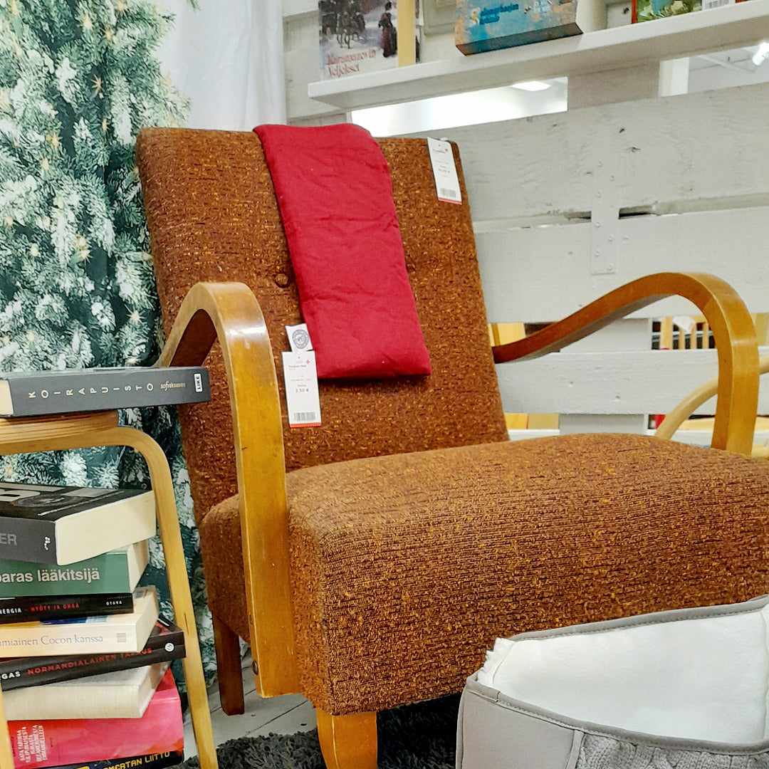 Ruskea retro nojatuoli, jonka vieressä pino kirjoja.