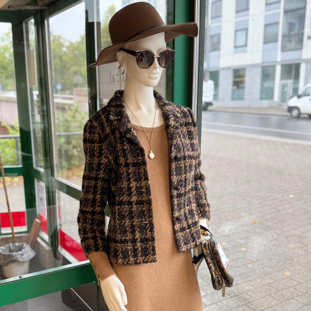 Mallinuken päällä naisten tyylikäs ruskeasävyinen vaatekokonaisuus, neulemekko, jakku, lierihattu ja aurinkolasit.