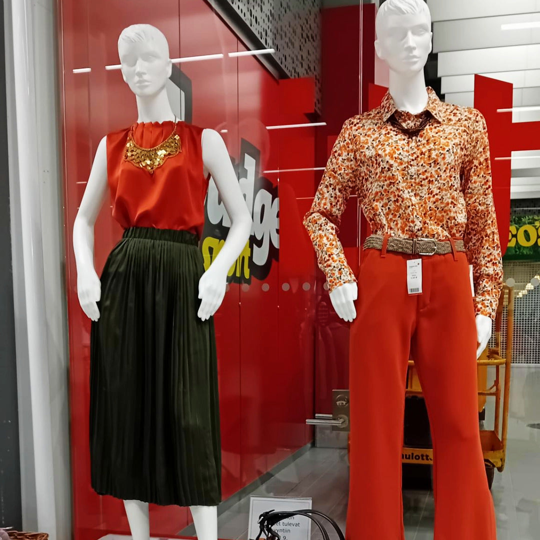 Kaksi mallinukkea, joilla on punaisia, osansseja ja mustia naisten vaatteita.