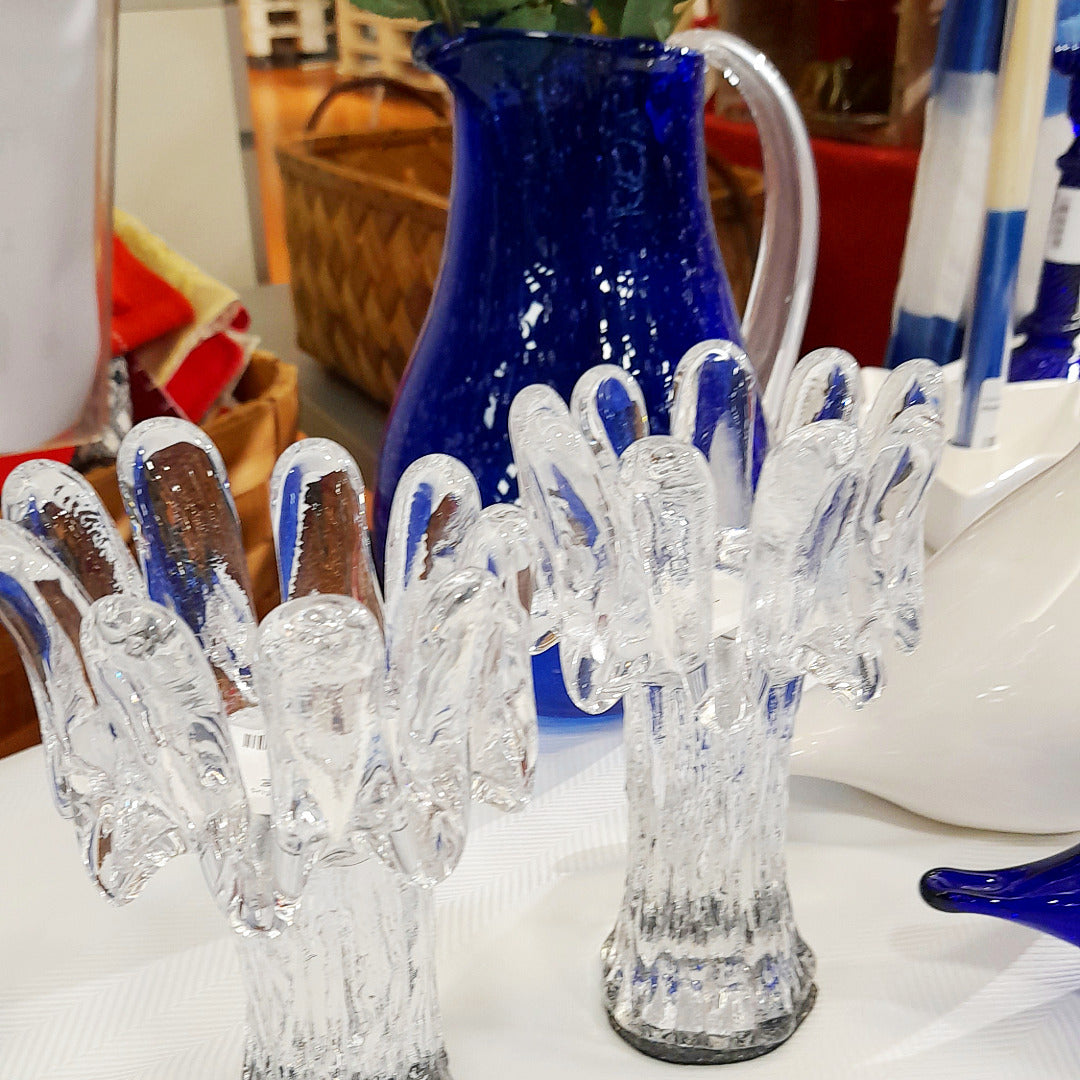 Kaksi muhkeaa kirkasta tuikkulyhtyä, takana sininen mehukannu.