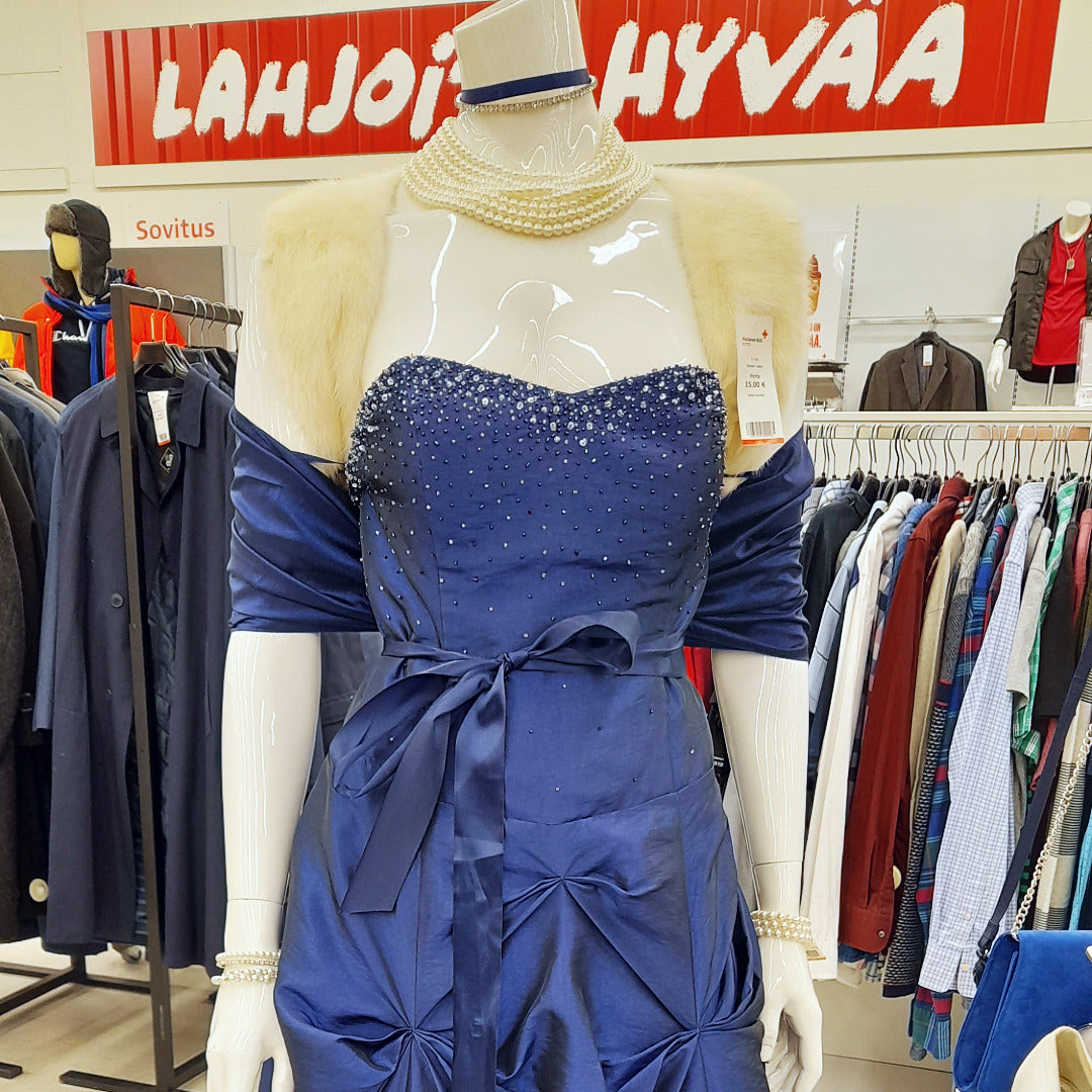 Sininen juhlamekko mallinuken päällä, taustalla miesten osaston vaatteita rekeissä.