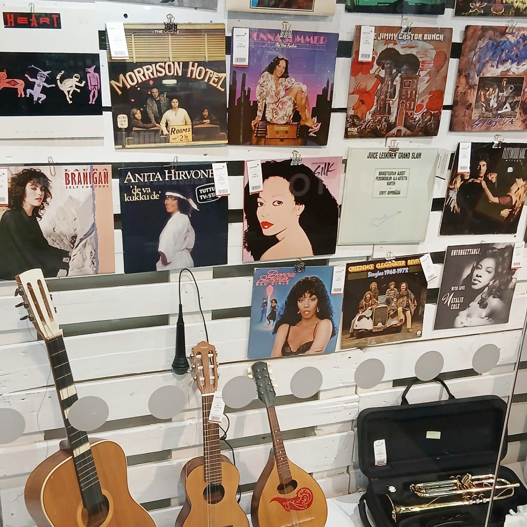 LP-levyjä seinällä, alhaalla kitaroita ja trumpetti.