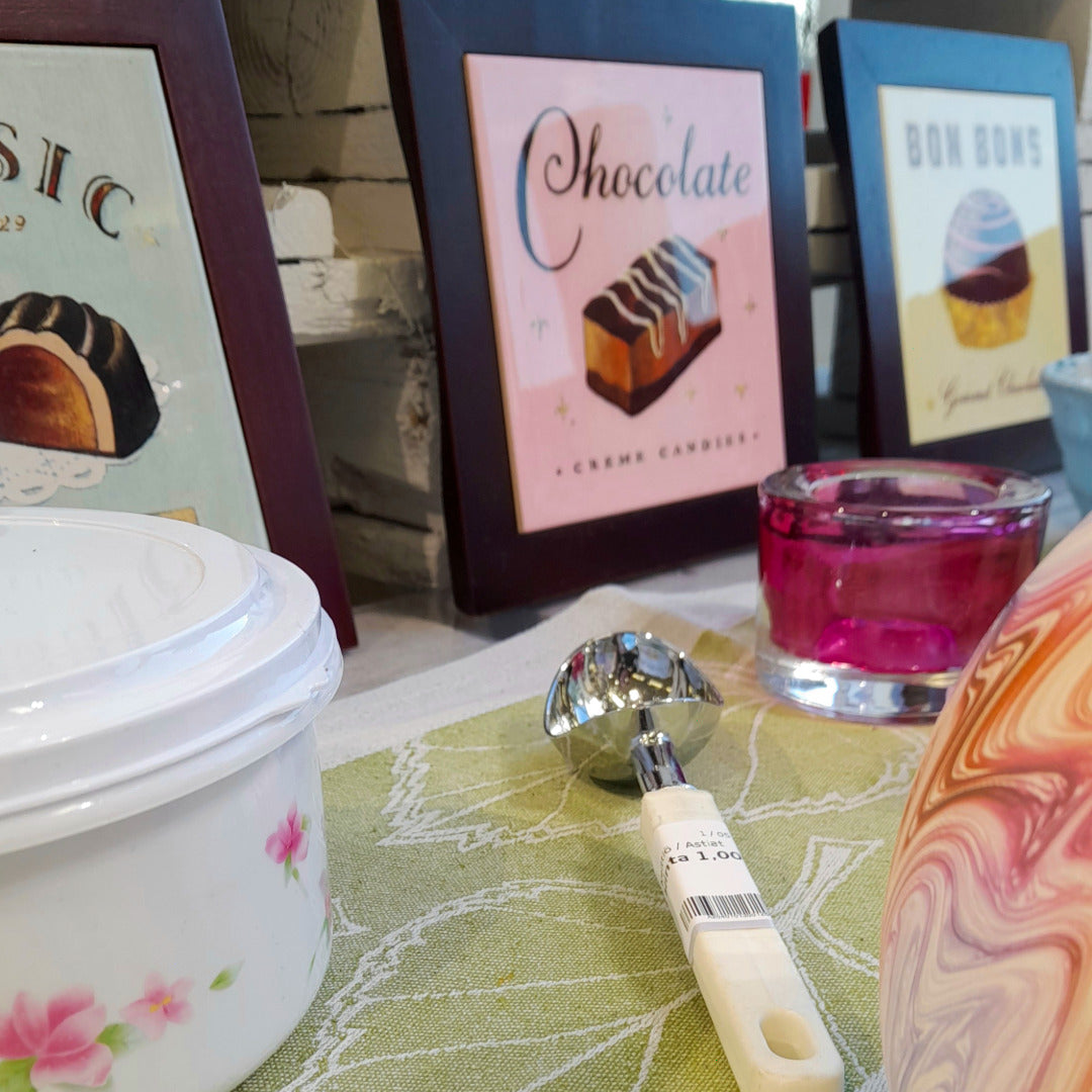 Suklaa-aiheisia sisustustauluja, lasinen tuikkukippo ja jäätelölusikka