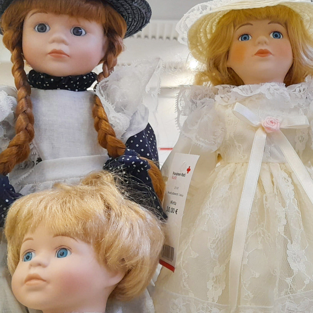 Kolme nukkea tyylikkäissä vanhanajan vaatteissa.