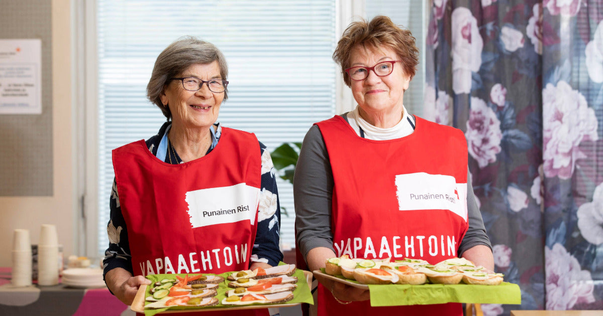 Kaksi SPR:n vapaaehtoista tarjoilee voileipiä.